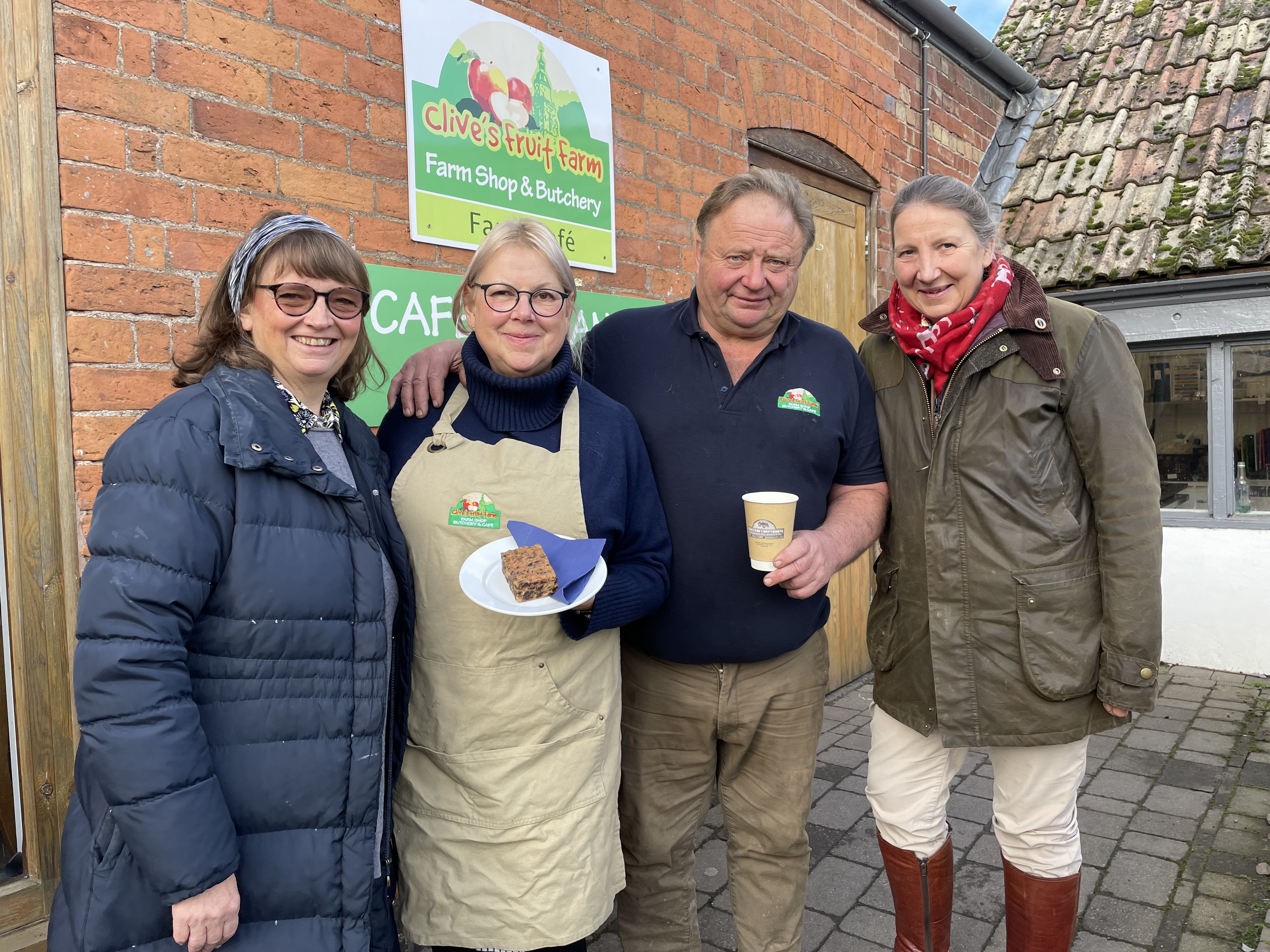 Three women and one man standing outside Clive's Fruit Farm cafe.