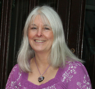 Photo of woman with shoulder length grey hair wearing a purple top